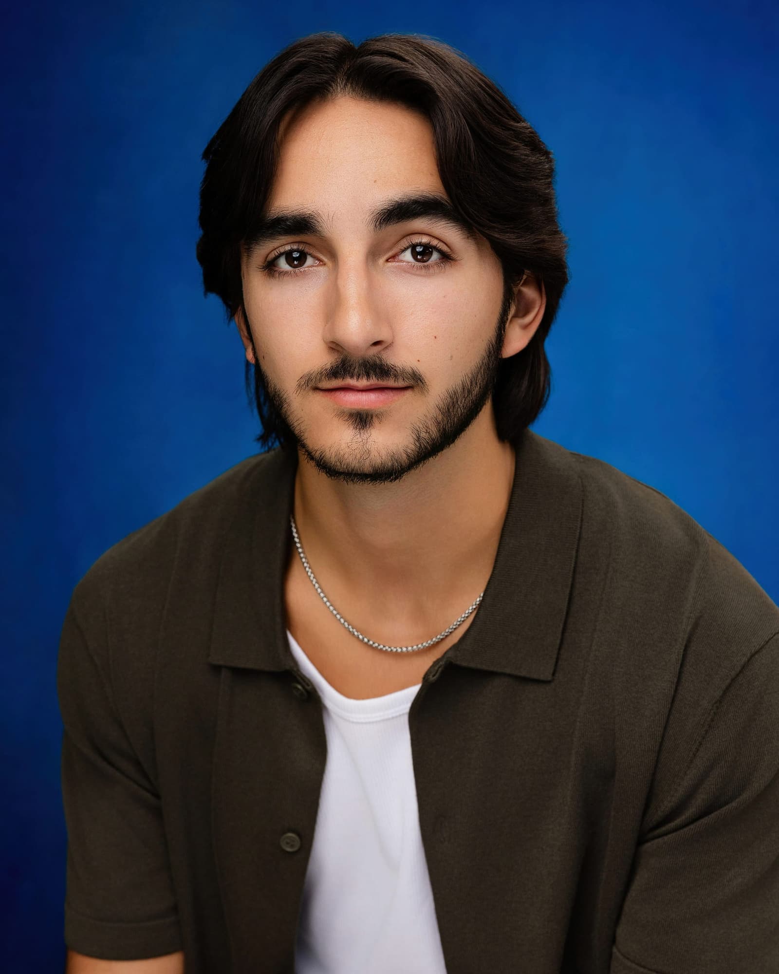Reid Salvador headshot in an olive overshirt against a blue backdrop